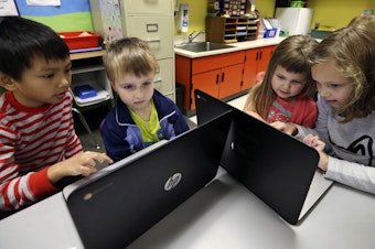 caption: In this photo taken Nov. 4, 2015, second grader Josh Mercado, left, helps kindergartner Erik Hodges, as second grader Annabelle Davis, right, helps kindergartner Kaidyance Harris, on programming during their weekly computer science lesson at Marshall Elementary School in Marysville, Washington.