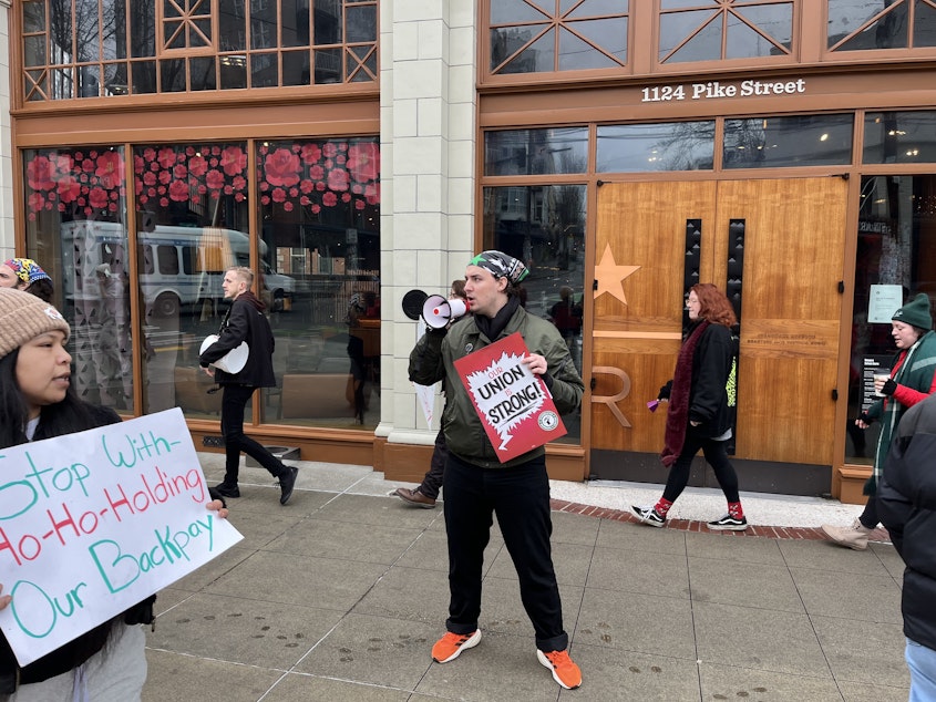 caption: Brennan Collins, one of the original organizers at the Reserve Roastery, leads a chant Friday.