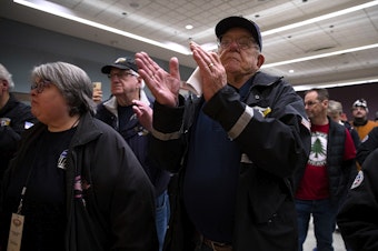 caption: Retired Boeing worker Jim Hutchins claps after John Holden, IAM District 751 President, announced that the machinists union accepted the latest contract offer from Boeing by 59 percent, on the 53rd day of the strike, on Monday, November 4, 2024, at the IAM 751 Seattle Union Hall. 