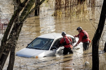 caption: San Jose: Search and rescue workers check a car trapped in flooding after heavy rain caused the Guadalupe River to overflow its banks, Sunday.