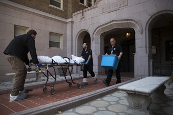 caption: A body is removed from an apartment on Monday, September 4, 2018, at the Malloy Apartments near the intersection of Northeast 43rd Street and 15th Avenue Northeast in Seattle.