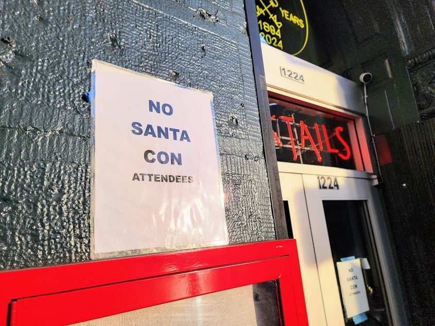 caption: A sign outside Diller Room bar that reads, 'NO SANTA CON ATTENDEES'  on Dec. 7, 2024.