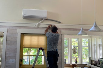 caption: CM Heating technician Hunter Morgan installs a heat pump in a house in Shoreline, Washington, in July 2023.