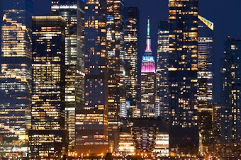 caption: The Empire State Building is lit in pastel colors to mark Easter as it stands between the towers of Hudson Yards in New York City on March 31.