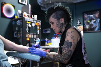 caption: Tattoo artist Dani Silva tattoos a customer on Thursday, August 15, 2024, at Side Quest Tattoo in Seattle. 