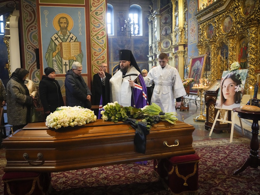 caption: A priest prays over the coffin of Oleksandra "Sasha" Kuvshynova, a Ukrainian journalist killed while working for Fox News in March 2022. Her parents have sued Fox News alleging wrongful death, fraud and defamation.