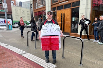 caption: Starbucks barista Mari Cosgrove strikes Friday in front of the Pike Street Starbucks Reserve Roastery in Seattle. 