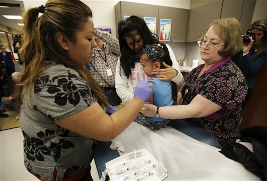 caption: Nurses Fatima Guillen, left, and Fran Wendt, right, give Kimberly Magdeleno, 4, a Tdap whooping cough booster shot in Tacoma, Washington in 2012.