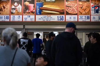 caption: Customers wait in line at a Costco food court in Hawthorne, California.
