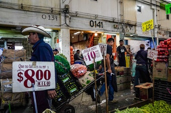 caption: Every day, 19,000 workers ferry produce around the Central de Abastos on dollies and wheelbarrows.