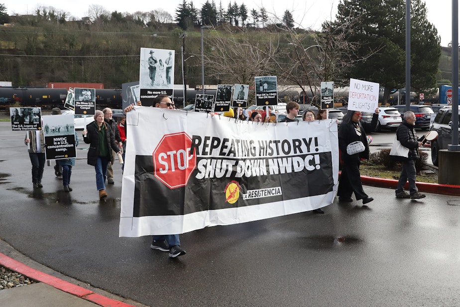 caption: About 40 Japanese Americans gathered at the King County International Airport on Tuesday, Feb. 21, 2024 and called for an end to deportation flights.