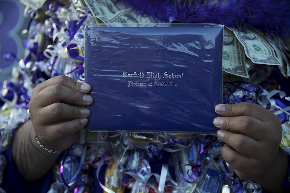 caption: Garfield High School senior Jabez Taualo holds his diploma after an in-person graduation ceremony on Tuesday, June 15, 2021, at Memorial Stadium in Seattle. "It's a true honor to be here today," said Taualo.