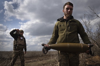 caption: Ukrainian soldiers carry shells to fire at Russian positions on the front line, near the city of Bakhmut, in Ukraine's Donetsk region, on March 25. The outgunned and outnumbered Ukrainian troops have been struggling to halt Russian advances.