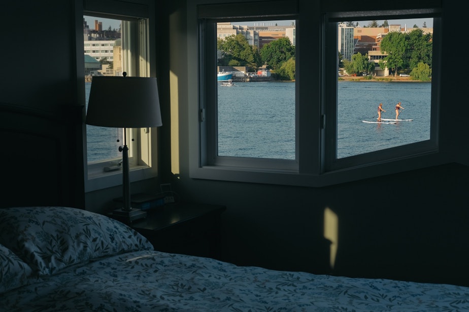 caption: Stand up paddle boarders on Portage Bay are seen passing from the bedroom window of Carol and Carl Buchan's floating home on Shelby dock, September 7, 2021.