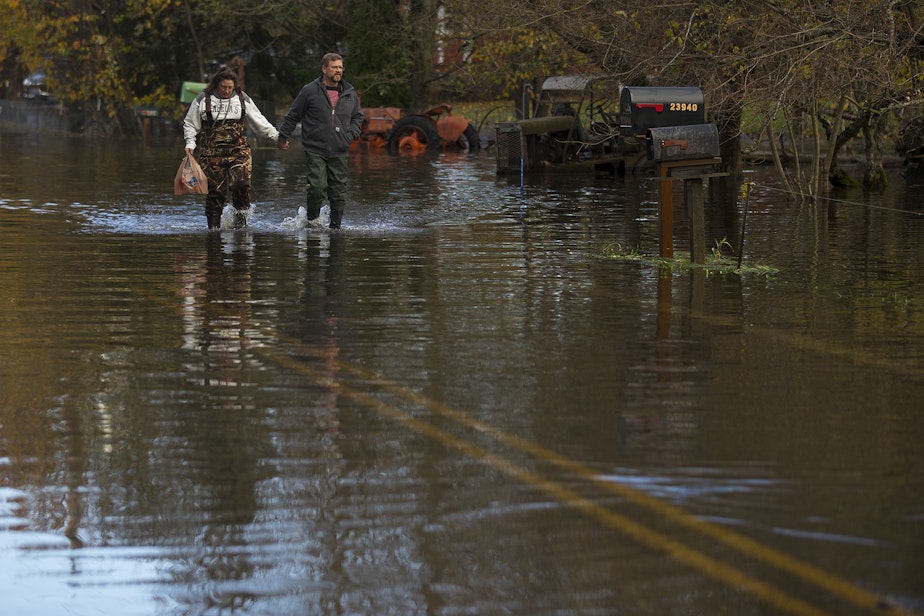 caption: Robby and Sara Burt walk through a flooded stretch of Old Day Creek Road toward Robby's mother's home, on Tuesday, November 16, 2021, in Clear Lake. 