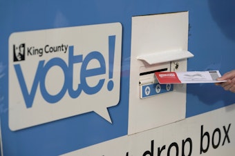 caption: A person puts their ballot in a drop box on Oct. 27, 2020, at a library in Seattle. 