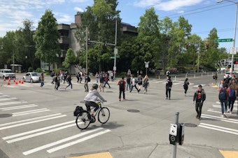 caption: An all-way crosswalk — with people walking straight-across and diagonally — at 15th Avenue Northeast and Northeast 40th Street in Seattle's University District.