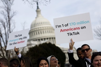 caption: People hold signs in support of TikTok outside the U.S. Capitol Building on March 13.