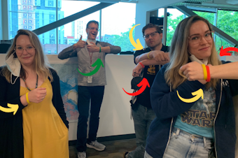 caption: KUOW's Katie Campbell, Bill Radke, Dyer Oxley, and Libby Denkmann show off their wristbands — worn around the KUOW office to show individual comfort levels as people navigate pandemic social settings. 