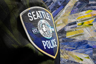 caption: A collage of a Seattle Police patch on an officer's uniform against a newspaper texture background. Original photo courtesy of the Seattle Police Department.