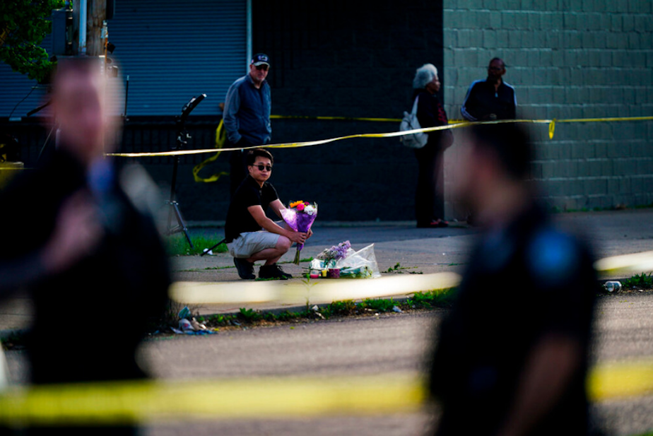 caption: A person places flowers outside the scene of a shooting at a supermarket in Buffalo, N.Y., Sunday, May 15, 2022. 