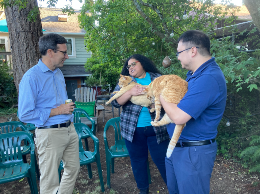 caption: Bob Ferguson, left, meets two orange cats at a backyard fundraising event in August 2024.