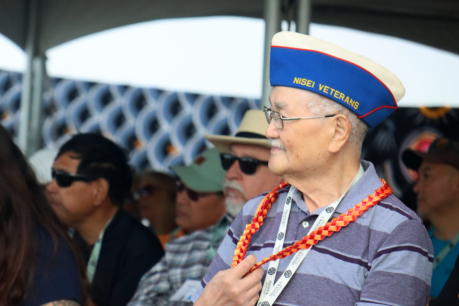 caption: Kay Endo, a survivor and veteran, touches the necklace that was given to all the survivors during a ceremony at the Minidoka National Historic Site in Idaho.